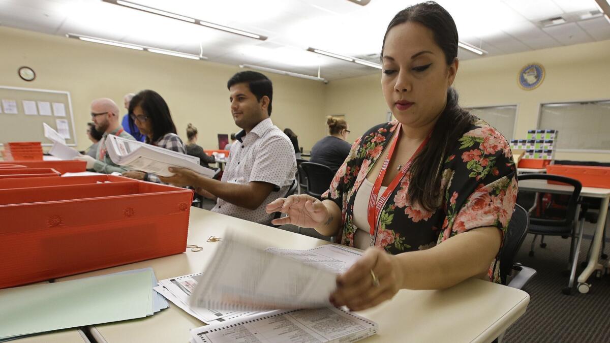 Bianca Savola, an election clerk at the Sacramento County Registrar of Voters, inspects a mail-in ballot.