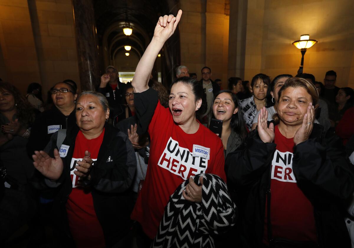 Rosa Aleman, center, a housekeeper with the Beverly Hilton hotel in Los Angeles, celebrates with other hospitality workers after the Los Angeles City Council voted to press forward with proposed regulations on short-term rentals.