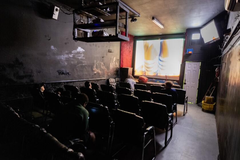 East Hollywood, CA - October 26: Men watch an adult film on the screen inside Tiki Theatre on Santa Monica Blvd. The XXX venue is believed to be the last porn theater in Los Angeles, photographed on Thursday, Oct. 26, 2023 in East Hollywood, CA. (Brian van der Brug / Los Angeles Times)
