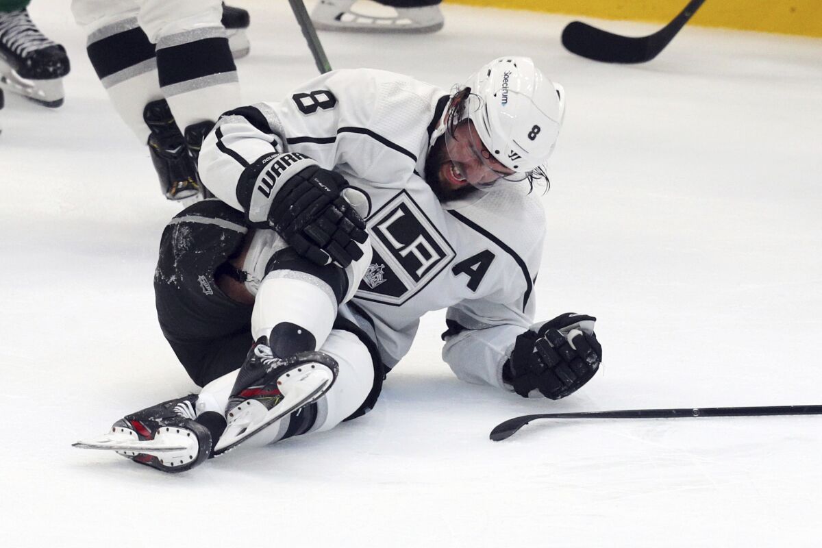 Los Angeles Kings defenseman Drew Doughty holds his knee as he lies on the ice.