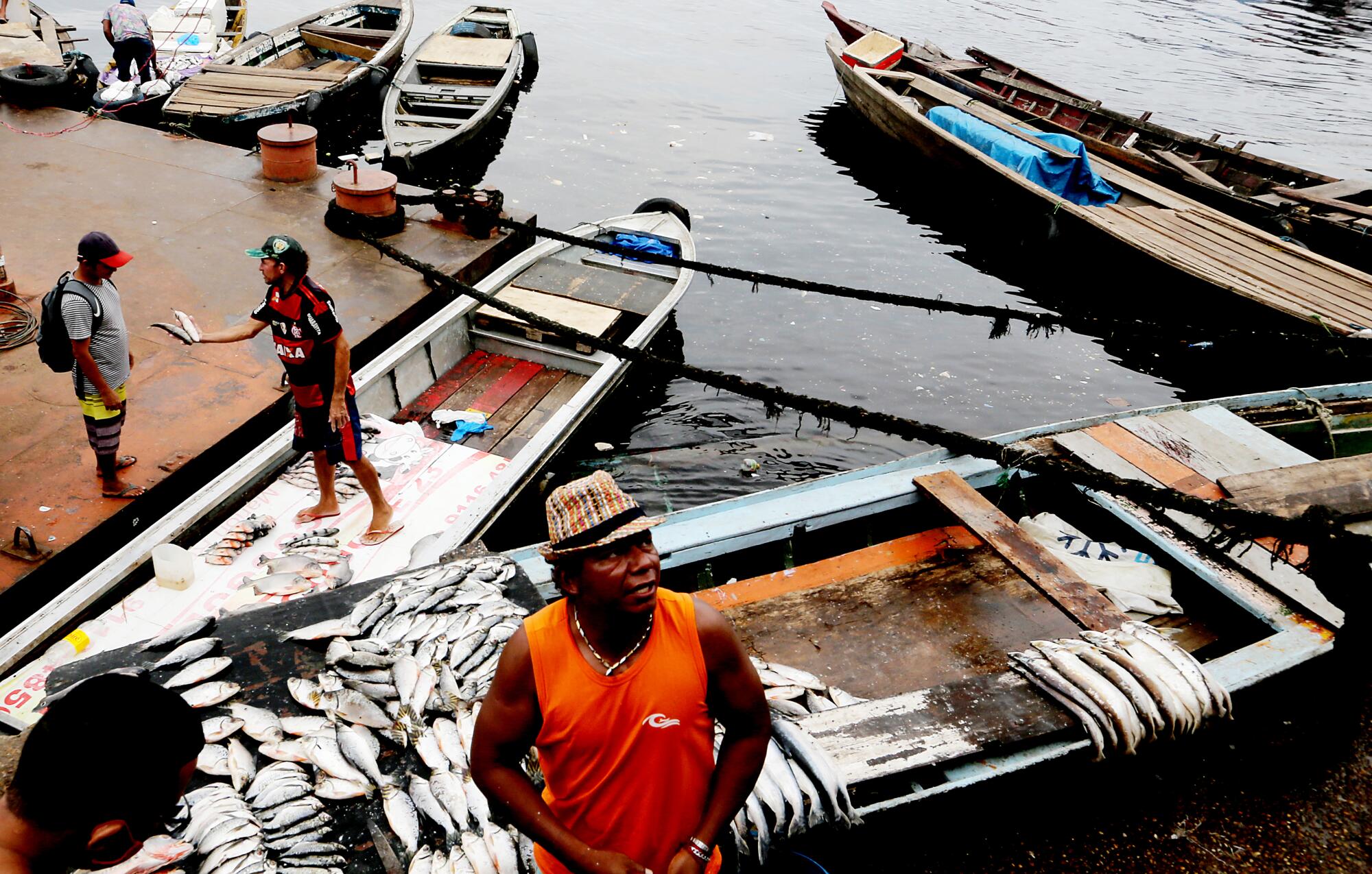 A man stands next to a boat with fish for sale  