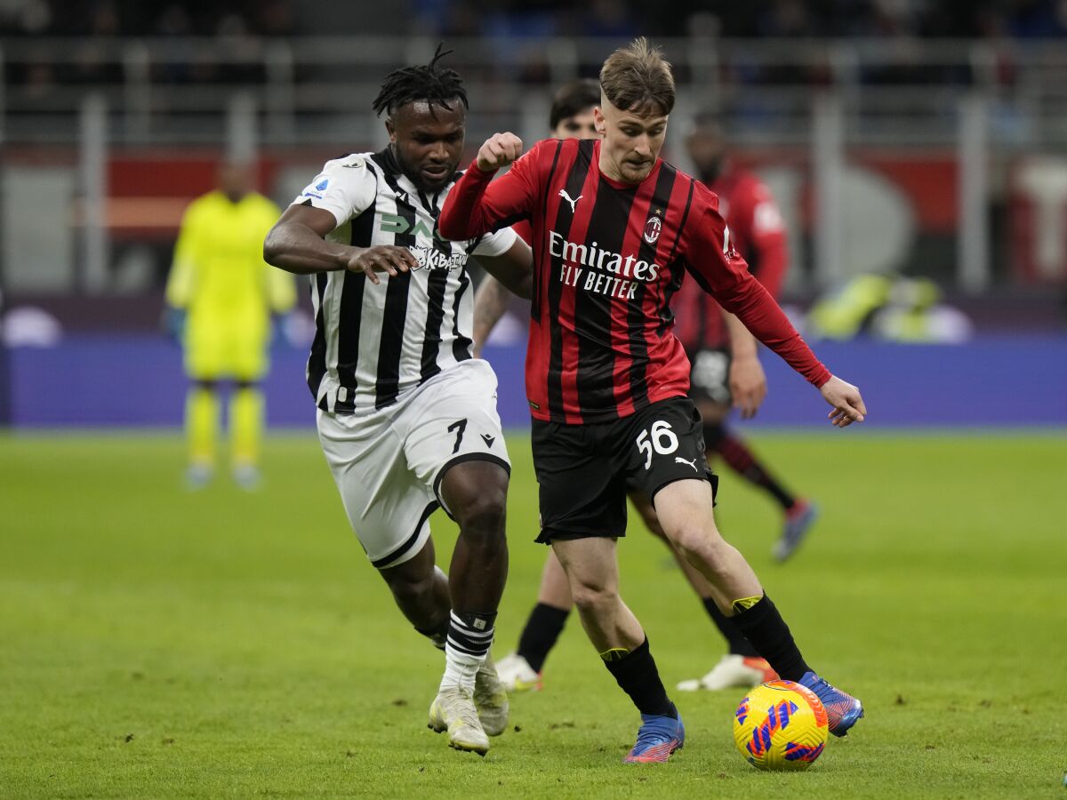 AC Milan's Alexis Saelemaekers, right, is challenged by Udinese's Isaac Success during a Serie A soccer match between AC Milan and Udinese, at the San Siro stadium in Milan, Italy, Friday, Feb. 25, 2022. (AP Photo/Luca Bruno)