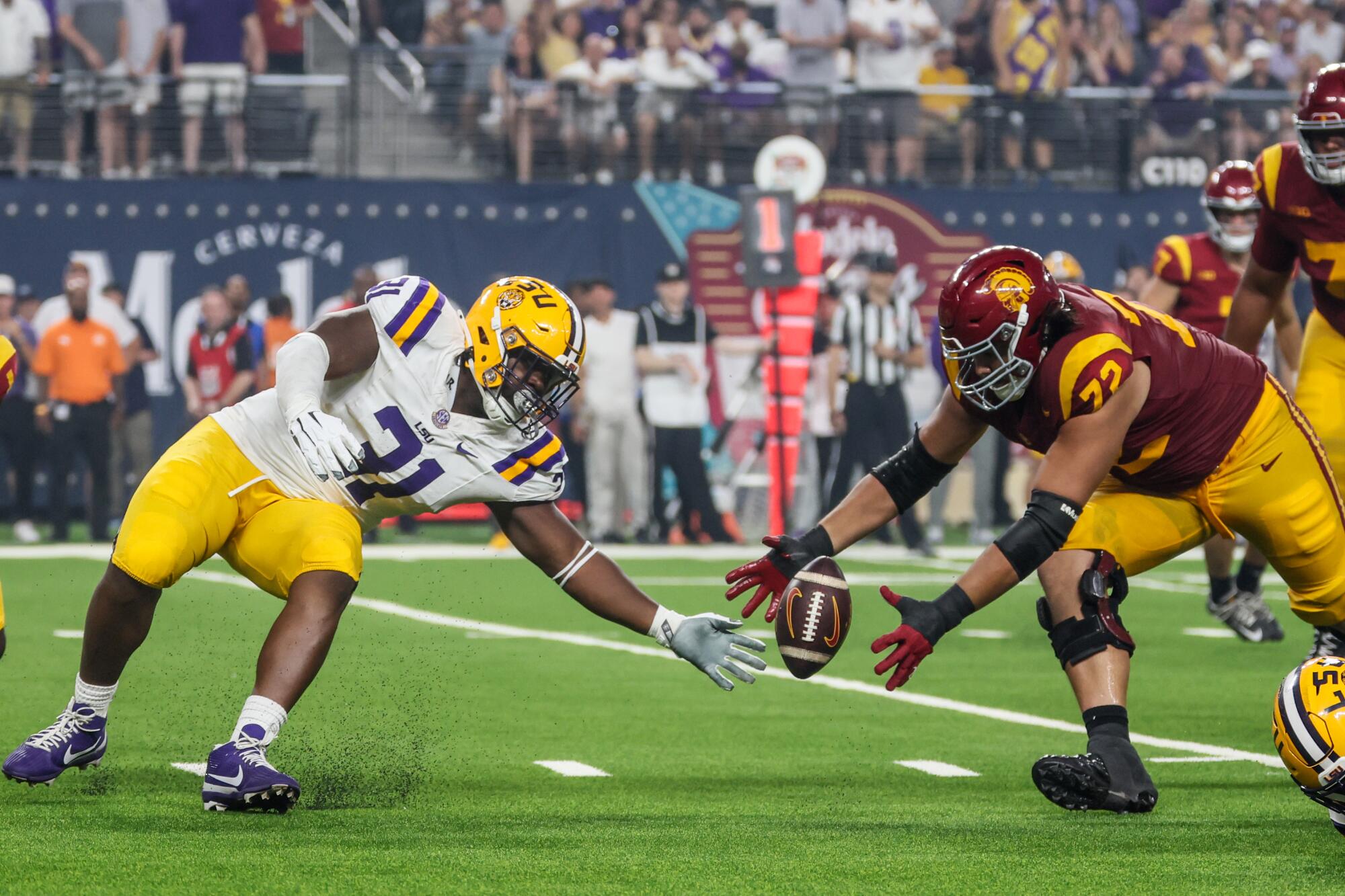  LSU Tigers defensive tackle Jay'viar Suggs and USC Trojans offensive lineman Elijah Paige reach for a muffed lateral.