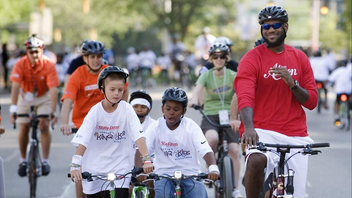 LeBron James, right, finishes his ride during the LeBron James Family Foundation, King for Kids Bike-a-thon, in Akron, Ohio, on Aug. 7, 2010.