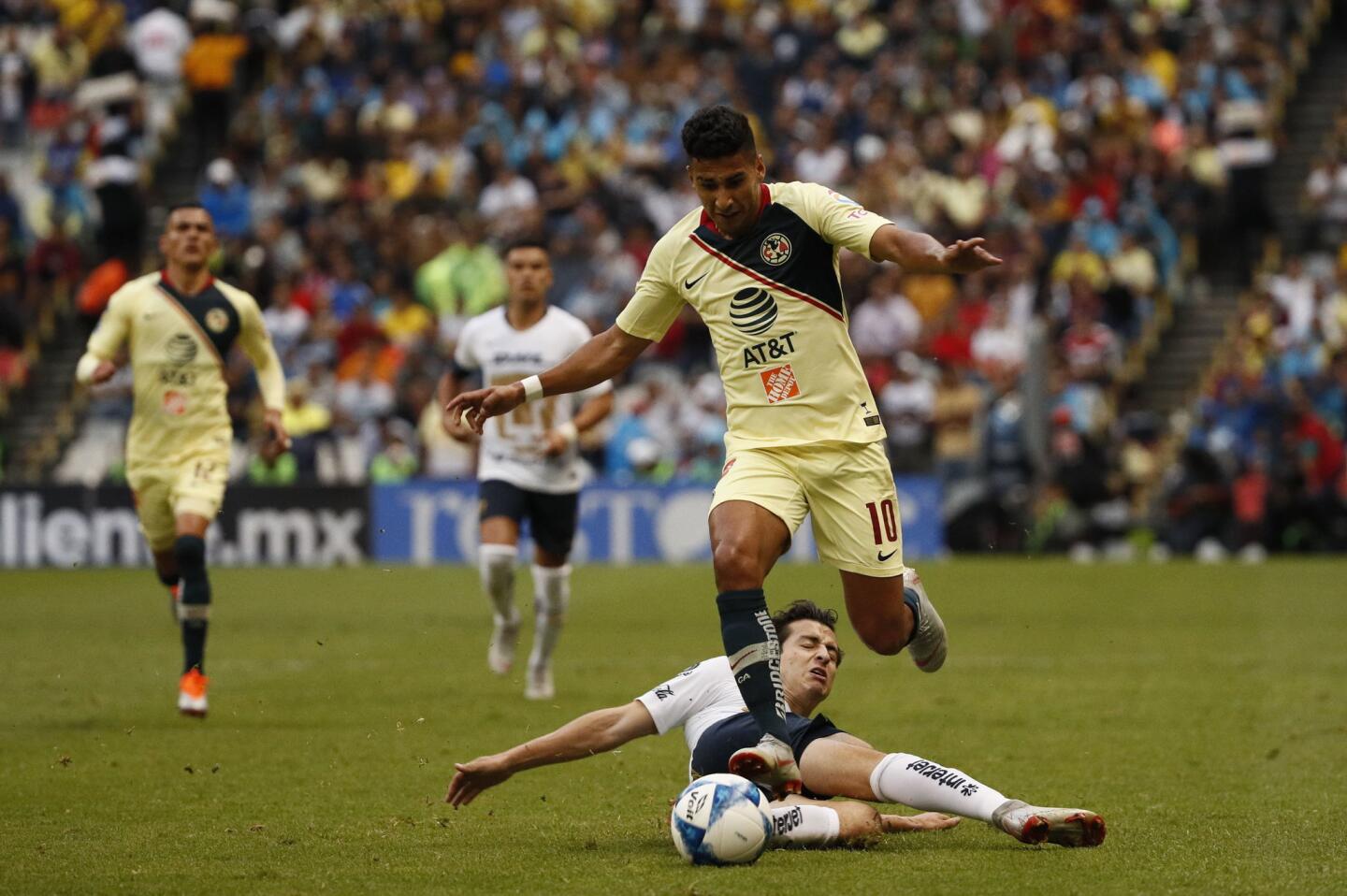El jugador Cecilio Domínguez (arriba) de América disputa el balón con Alan Mozo (abajo) de Pumas.