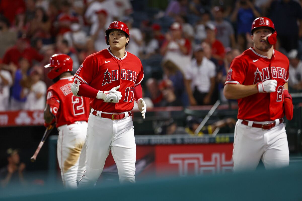 Angels teammates Shohei Ohtani, left, and Mike Trout jog back to dugout.