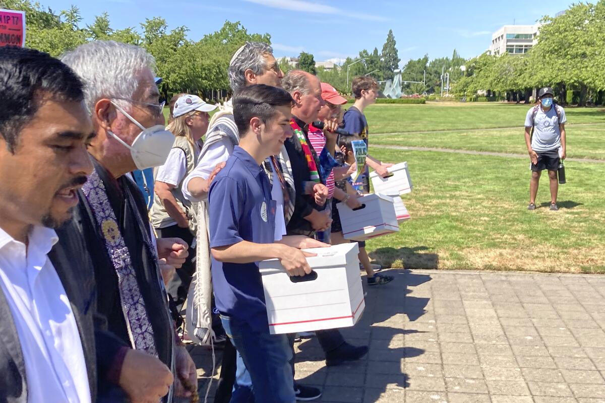 Backers of a proposed initiative that would require individuals to secure permits to buy firearms and ban large-capacity magazines deliver the signatures of thousands of voters on Friday, July 8, 2022, to state election offices in Salem, Oregon. The backers say concern about recent mass shootings have buoyed their effort and that they have enough signatures to place the measure on the November ballot. (AP Photo/Andrew Selsky)