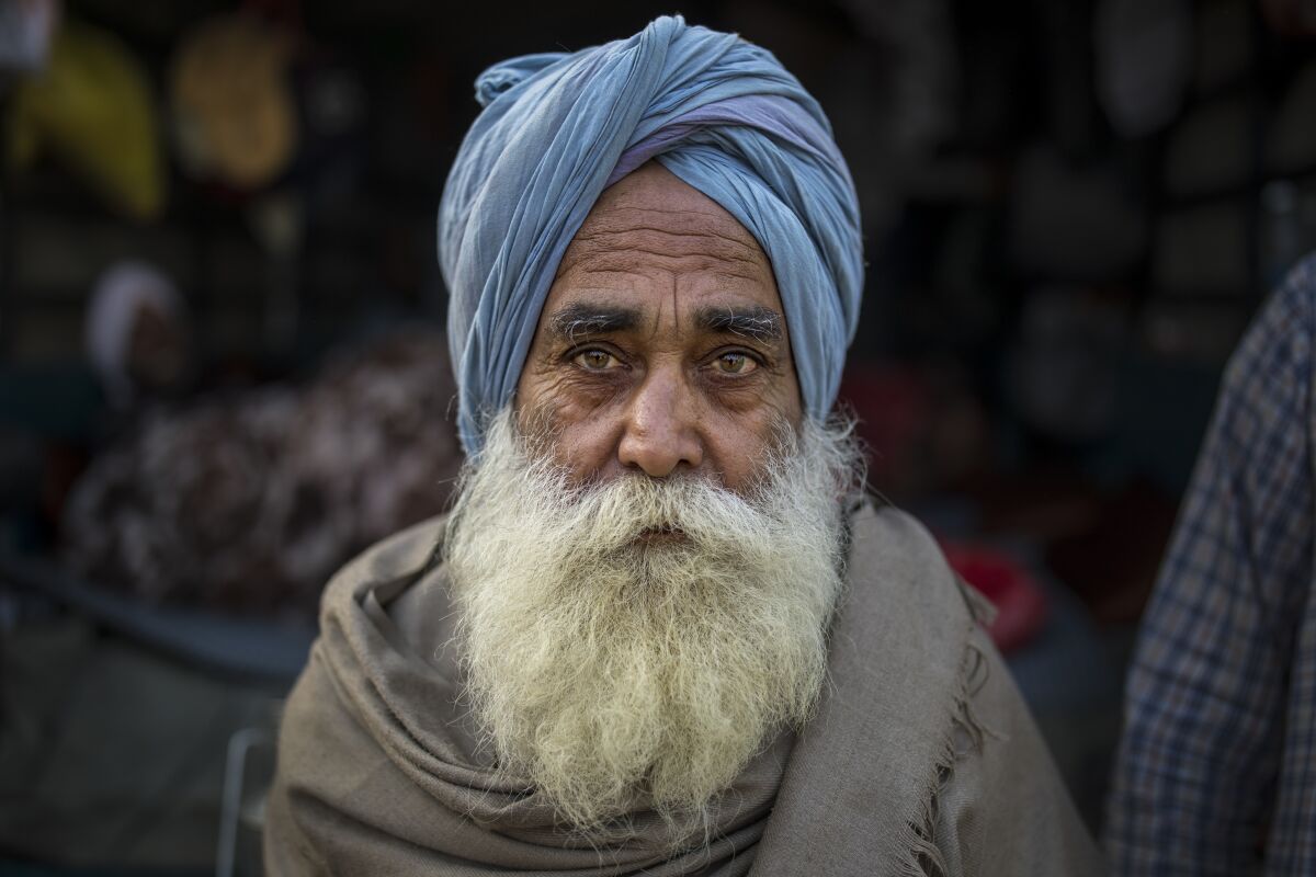 Jagtar Singh, 78, sits for a photograph on the back of his tractor trolley parked on a highway as he joins other farmers protesting against new laws they say will result in their exploitation by corporations, eventually rendering them landless, at the Delhi-Haryana state border, India, Tuesday, Dec. 1, 2020. Instead of cars, the normally busy highway that connects most northern Indian towns to the capital is filled with tens of thousands of protesting farmers, many wearing colorful turbans. Their convoy of trucks, trailers and tractors stretches for at least three kilometers (1.8 miles) in a siege of sorts and the mood among the protesting farmers is boisterous. Their rallying call is “Inquilab Zindabad” (“Long live the revolution”).(AP Photo/Altaf Qadri)