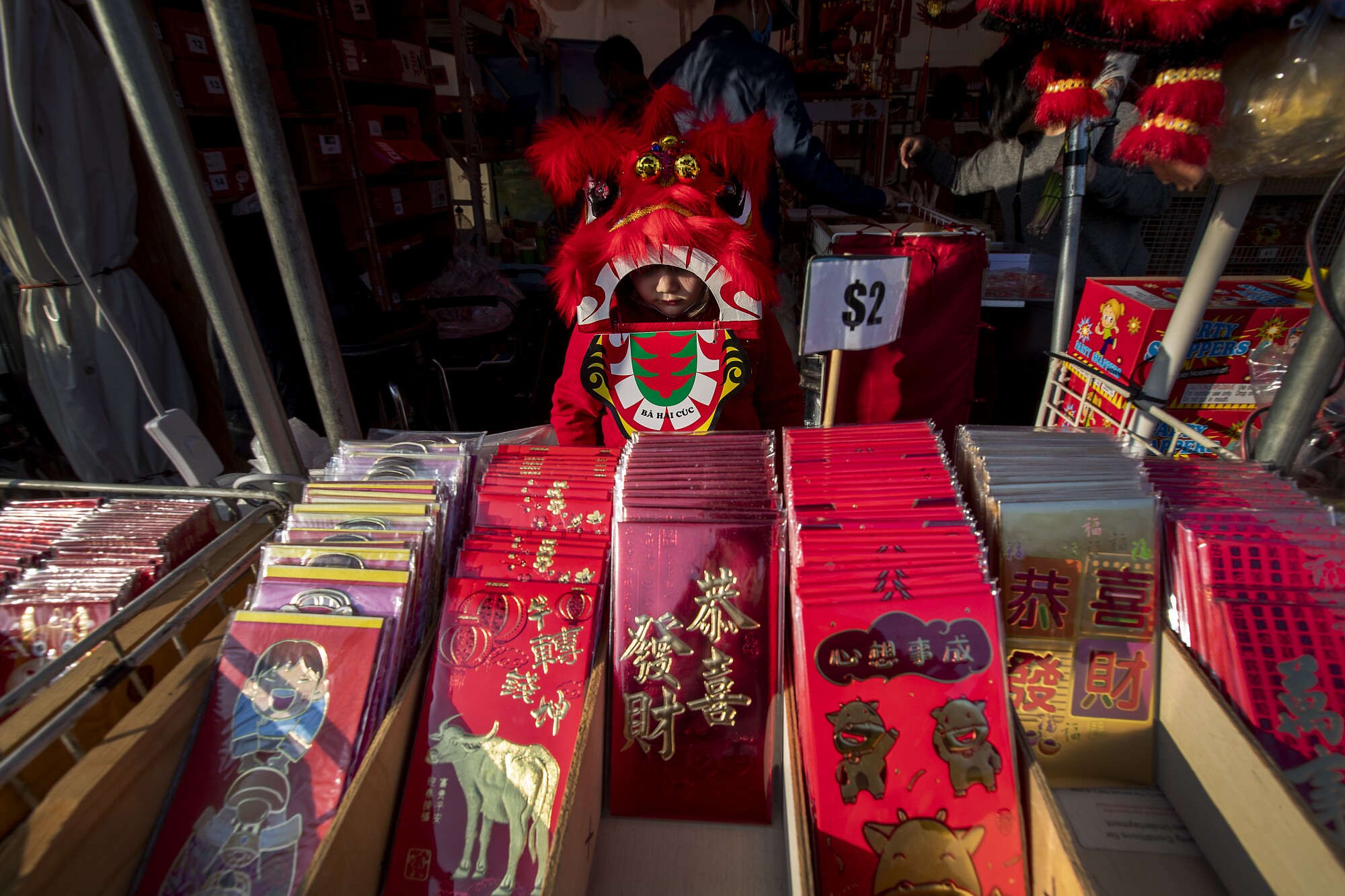 Midori Nguyen, 5, of Westminster, wears a lion dance costume while looking over li xi, or red envelopes