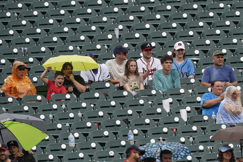 Baseball Fans sit in the rain as they watch a baseball game between the Atlanta Braves and the Tampa Bay Ray,s Sunday, July 18, 2021, in Atlanta. (AP Photo/John Bazemore)