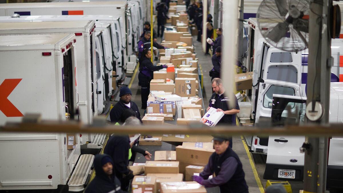 Workers sort packages on a conveyor belt before loading them onto trucks for delivery at a FedEx facility in Marietta, Ga., in 2014.