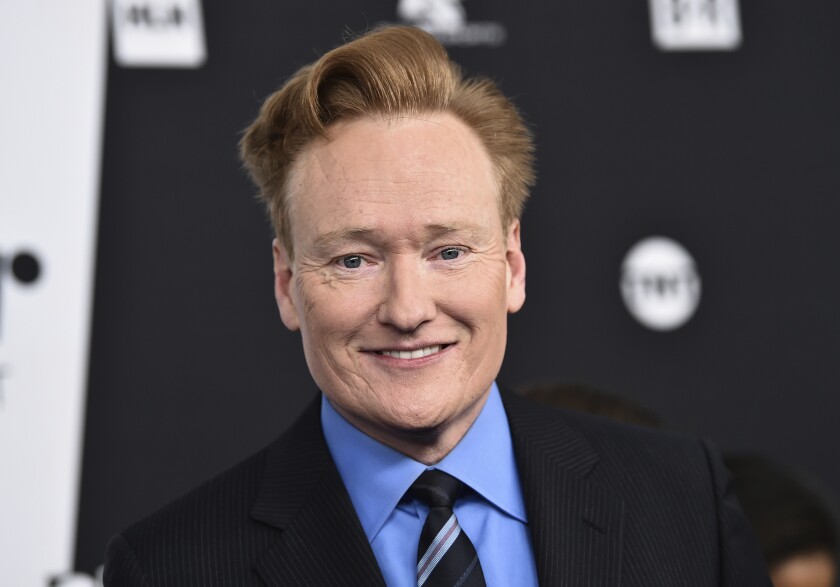 A man with short red hair smiling in a suit