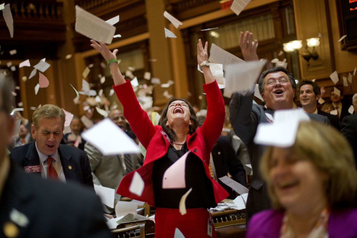 Georgia Republican state legislators Mandi Ballinger, center, Terry Rogers, left, and Rick Jasperse, right, throw up paper from their desks at the conclusion of the legislative session in the House chamber in Atlanta.