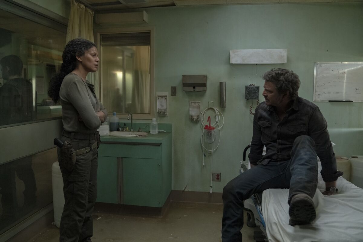 A woman talking to a man sitting on a hospital bed.