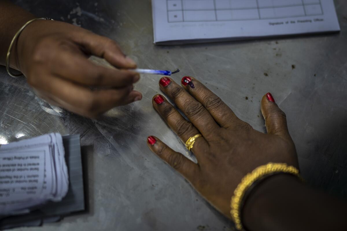 A polling official in Chennai, India, puts an indelible ink mark on the index finger of a woman as she arrives to vote.