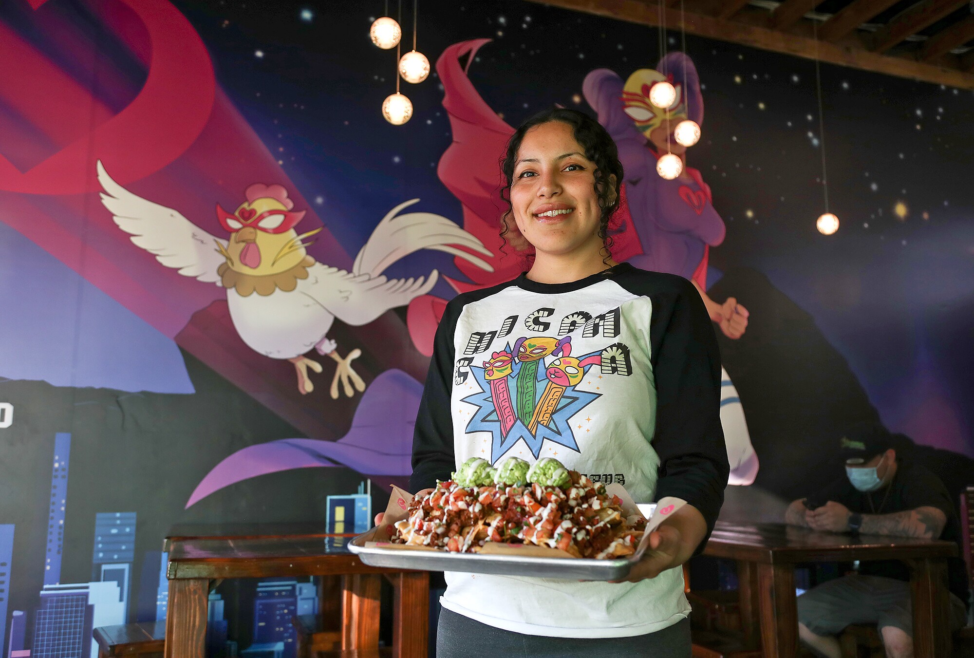 Jasmine Hernandez of Chicana Plant-based Grub in Fullerton holds a plate of the loaded nachos.