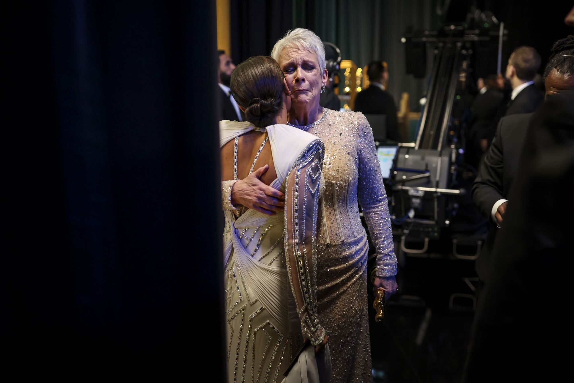 A woman comforts a tearful woman backstage at the Oscars.
