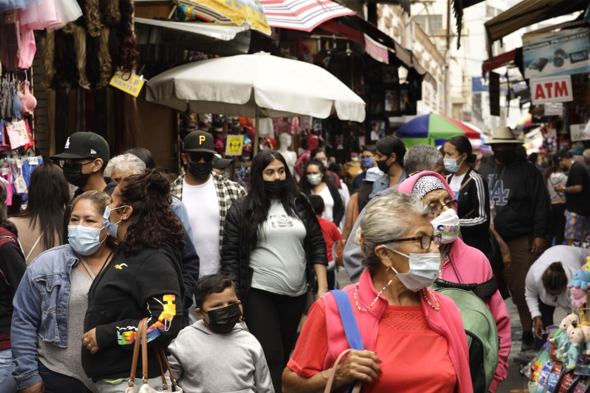 Masked people walk through an outdoor shopping area.
