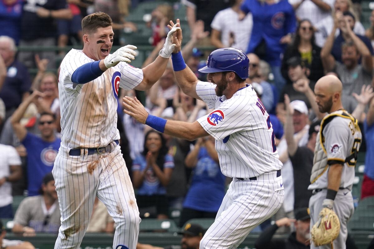 Chicago Cubs' Frank Schwindel, left, celebrates with Alfonso Rivas, center, after hitting the game-winning single as Pittsburgh Pirates catcher Jacob Stallings looks down in the ninth inning of a baseball game in Chicago, Saturday, Sept. 4, 2021. The Cubs won 7-6. (AP Photo/Nam Y. Huh)