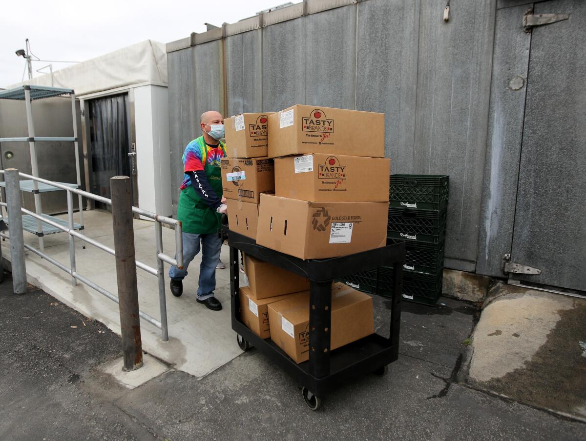 A Burbank Unified driver retrieves more items from a large cooler to prepare five-day meal packages for students across the district, at Burbank Middle School on Tuesday.