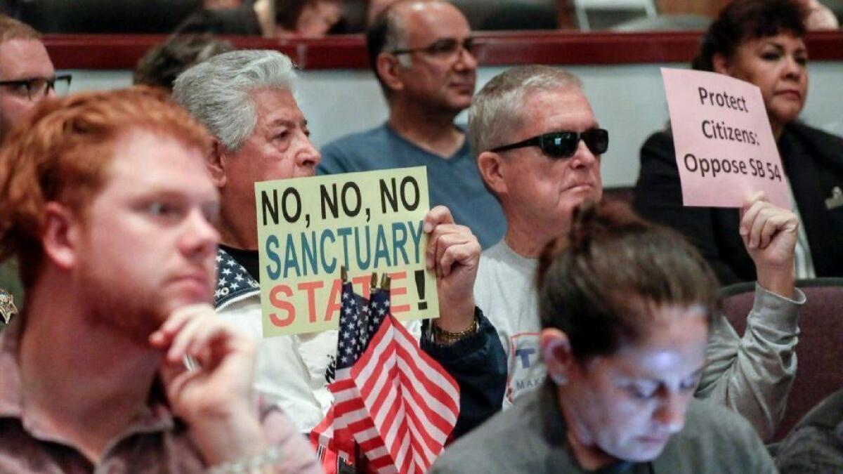 People oppose so-called “sanctuary state” laws during the Orange County Board of Supervisors meeting in Santa Ana on Tuesday. Huntington Beach is scheduled to discuss its potential opposition to the laws on Monday.