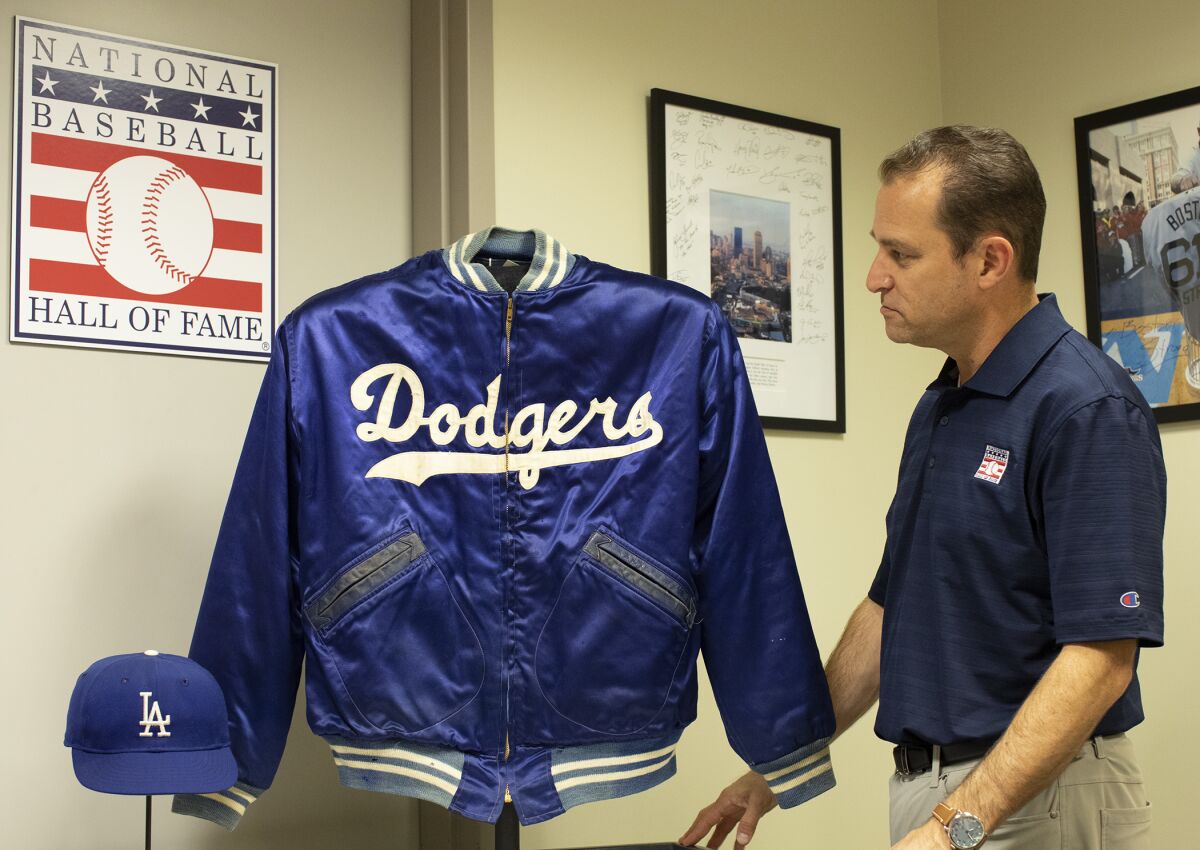 Josh Rawitch looks at a jacket and cap belonging to Dodgers legend Duke Snider.