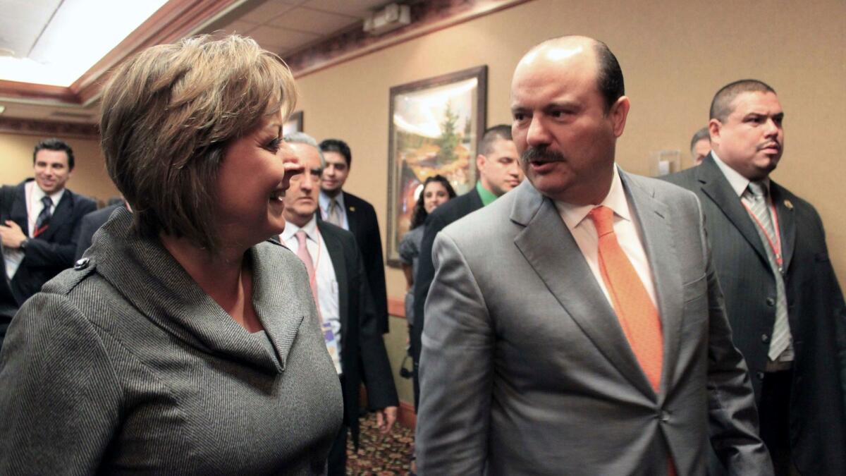 New Mexico Gov. Susana Martinez, left, and Cesar Duarte talk in Albuquerque in 2012. Mexico's federal officials will take over an investigation into Duarte, who is accused of diverting public funds.