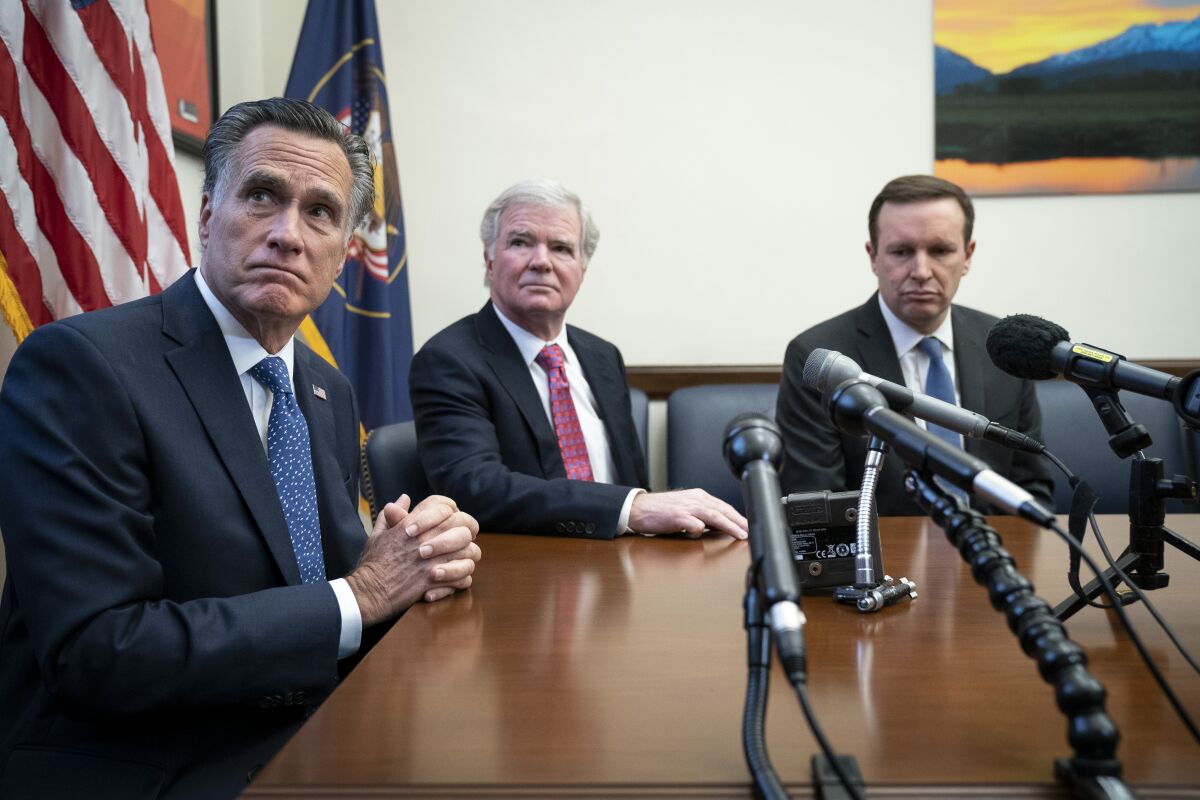 NCAA President Mark Emmert is flanked by Sens. Mitt Romney, left, and Chris Murphy during a news conference Dec. 17, 2019, in Washington.