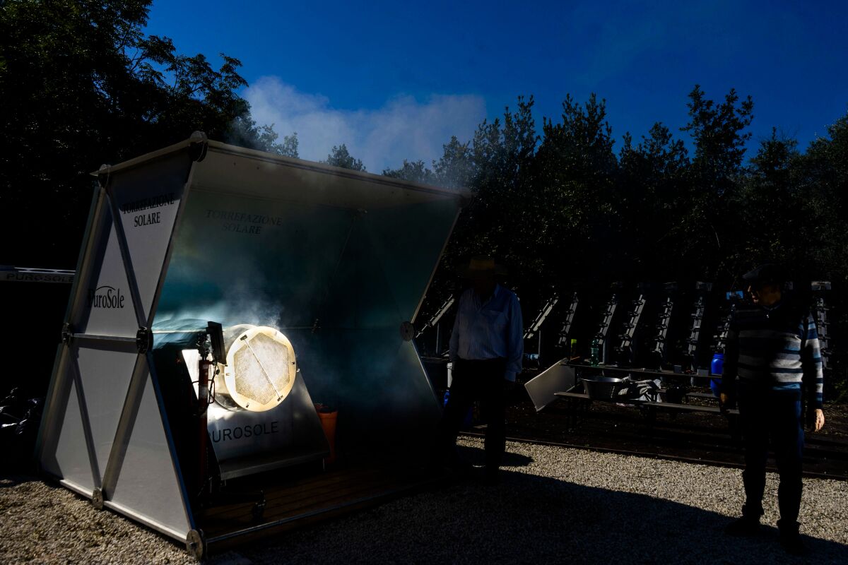 Antonio Durbe, left, and Daniele Tummei overlook the functioning of the "Purosole", Pure Sun, solar light coffee roaster, in Rome, Wednesday, Oct. 13, 2021. Two electrical engineers, Antonio Durbe and Daniele Tummei, invented a plant that just needs a piece of land about the size of half a tennis court and sunny weather to toast up to 50kg of coffee an hour. No gas, no electricity, just sun rays concentrated by a set of mirrors on a rotating steel basket filled of fresh coffee grains. (AP Photo/Michele Calamaio)