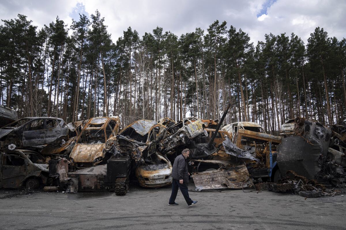 A man walks past a storage place for burned armed vehicles and cars, on the outskirts of Kyiv, Ukraine, Monday, April 11, 2022. (AP Photo/Evgeniy Maloletka)
