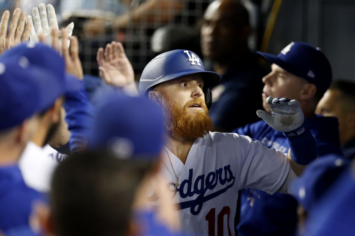 Dodgers designated hitter Justin Turner celebrates with teammates in the dugout after hitting a two-run home run.