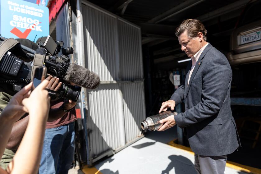 State Sen. Brian Jones, R-Santee, shows a catalytic converter to members of the media at Barrio Auto Service in Sherman Heights on Friday, March 18, 2022. Jones introduced a bill, SB 919, that would require dealers to permanently mark catalytic converters with a Vehicle Identification Number, require recyclers to purchase catalytic converters with an untampered VIN and increase fines for catalytic converter theft.