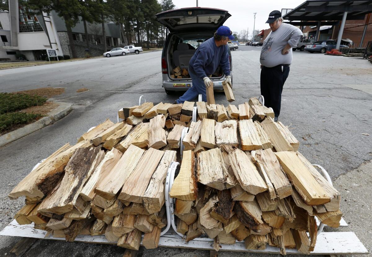 Billy Godboldt, left, loads firewood into Joe Hamm's van at the Woodshed lumberyard ahead of a predicted winter storm in Decatur, Ga., on Monday.