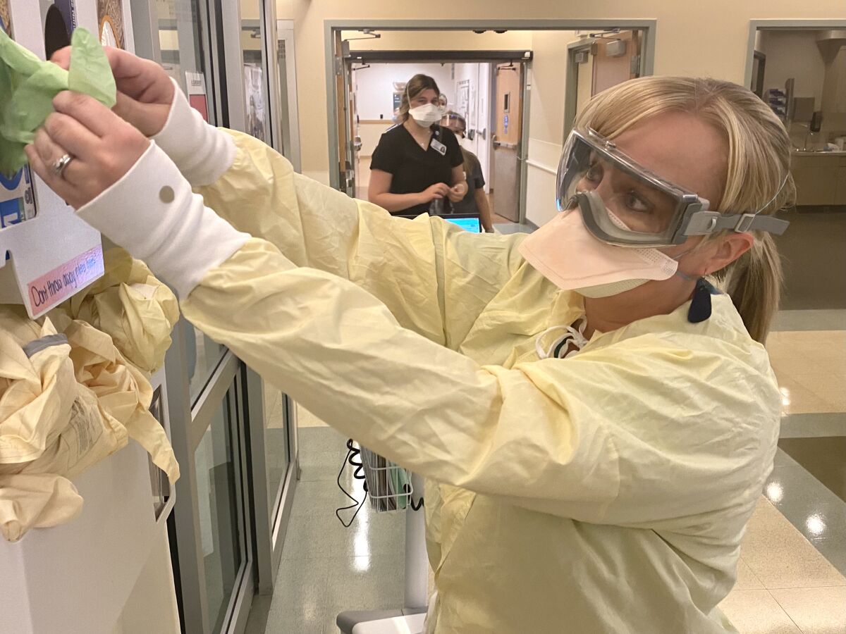 Woman dons protective gear during staffing shortage at St. Charles Medical Center in Bend, Ore.