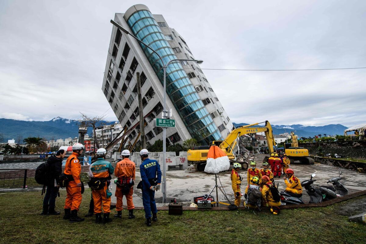 Japanese, left, and Taiwanese rescue workers look at the Yun Tsui building, which is leaning at a precarious angle, in the Taiwanese city of Hualien on Feb. 9 after the city was hit by an earthquake.