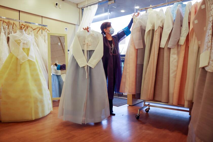 Laura Park displays some of the traditional Hanbok clothing available at her store in Koreatown.