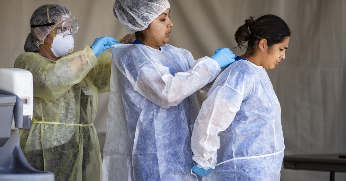 Riverside County medical personnel helping each other put on personal protective equipment.