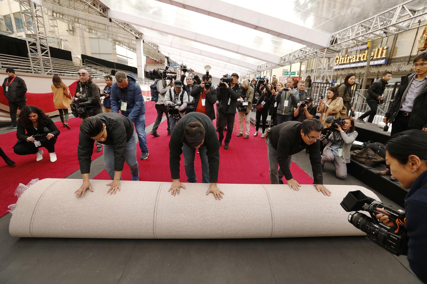 Estuardo Marrorquin, left, Sergio Marroquin and Rudy Morales roll out a portion of the red carpet on Hollywood Boulevard in front of the Dolby Theatre as preparations continue for the 91st Oscars show on Sunday.