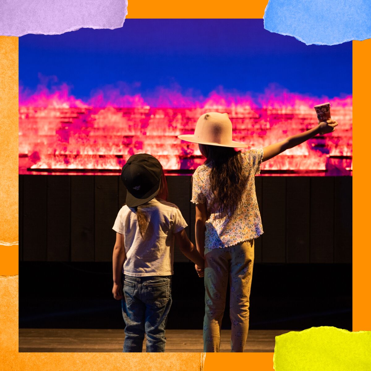 Two children in hats stand and hold hands in front of a glowing landscape.