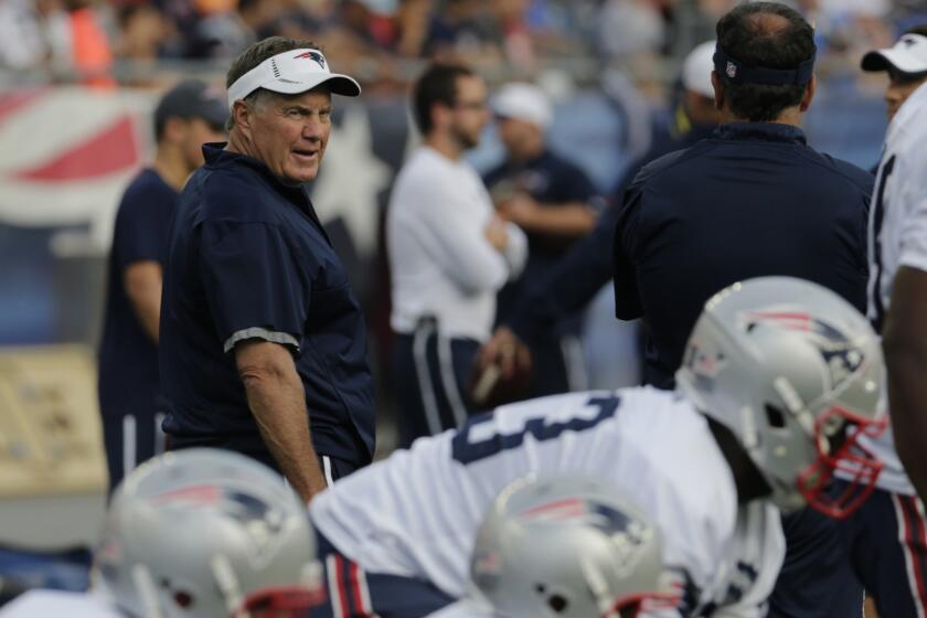 Patriots Coach Bill Belichick watches players warm up for a workout at training camp on Aug. 5.