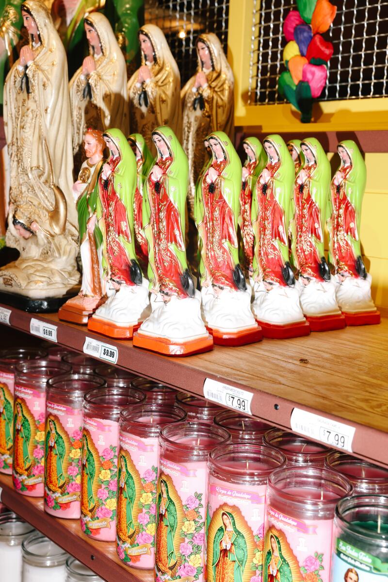 A photo of Virgin Mary statues and prayer candles on shelves.