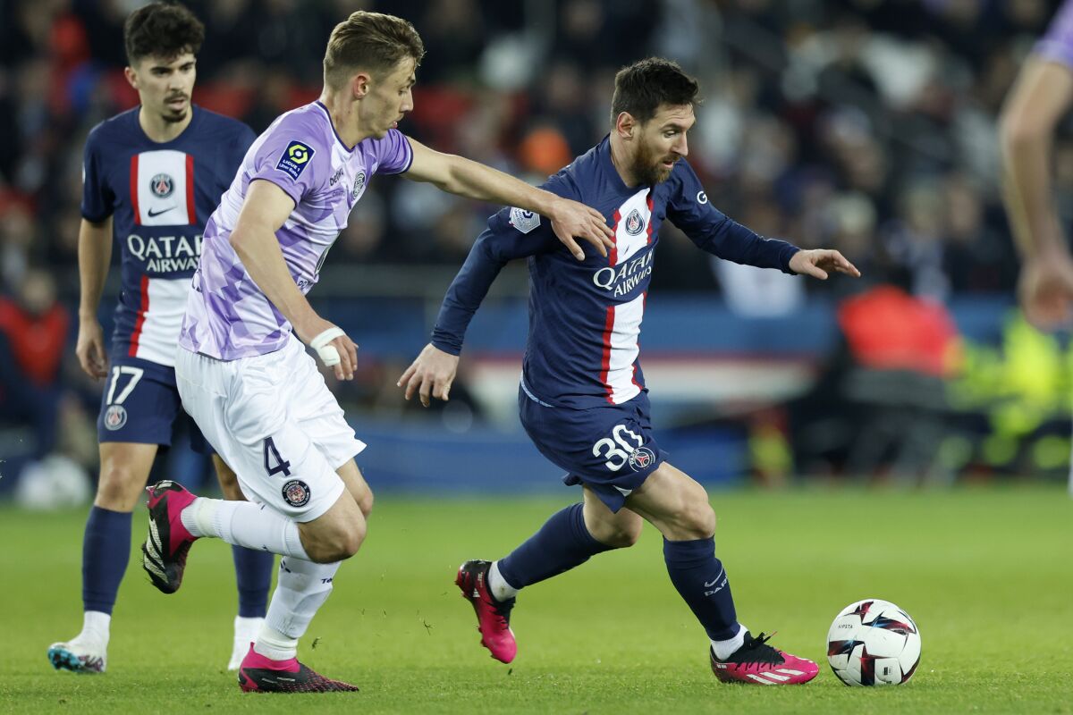PSG's Lionel Messi, right, runs with the ball next to Toulouse's Anthony Rouault during the French League One soccer match between Paris Saint-Germain and Toulouse, at the Parc des Princes, in Paris, France, Saturday, Feb. 4, 2023. (AP Photo/Lewis Joly)