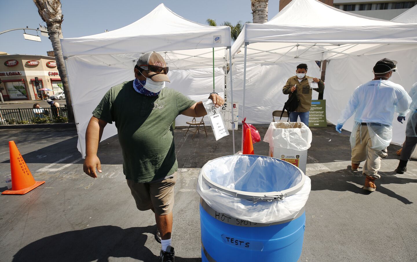 Carlos Miranda deposits his test for Coronavirus in the parking lot of a Food4Less Grocery in the Westlake area.