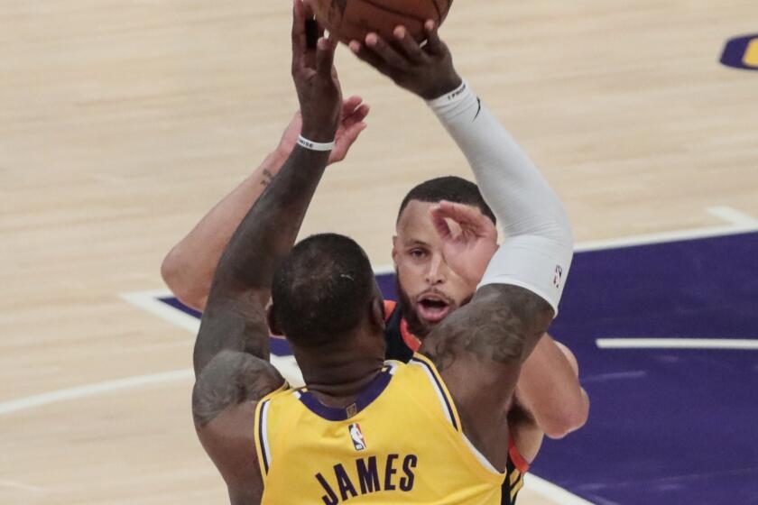 Lakers forward LeBron James shoots a three-pointer late in the game over Golden State Warriors guard Stephen Curry 