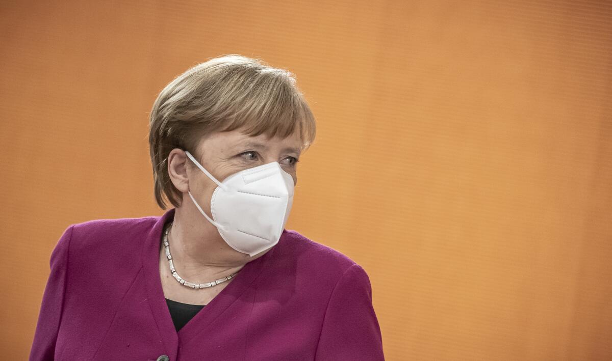 German Chancellor Angela Merkel takes off her mask at the beginning of the Federal Cabinet meeting at the Chancellery in Berlin, Germany, Wednesday, March 3, 2021. (Michael Kappeler/Pool via AP)