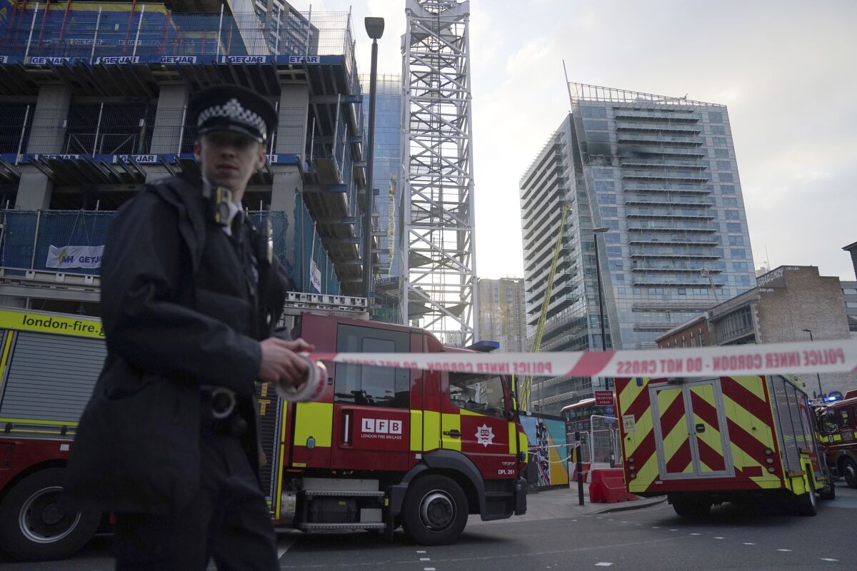 A police officer cordons off the area as emergency services attend to a fire which has broken out in a block of flats in east London, Monday, March 7, 2022. More than 100 firefighters tackled a blaze Monday on the 17th floor of a mixed-use building in east London. London’s Metropolitan Police said the building is being evacuated and road closures were in place in the Whitechapel area. (Victoria Jones/PA via AP)