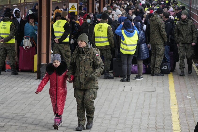 Un soldado acompaña a un niño mientras refugiados de Ucrania llegan a una estación de tren