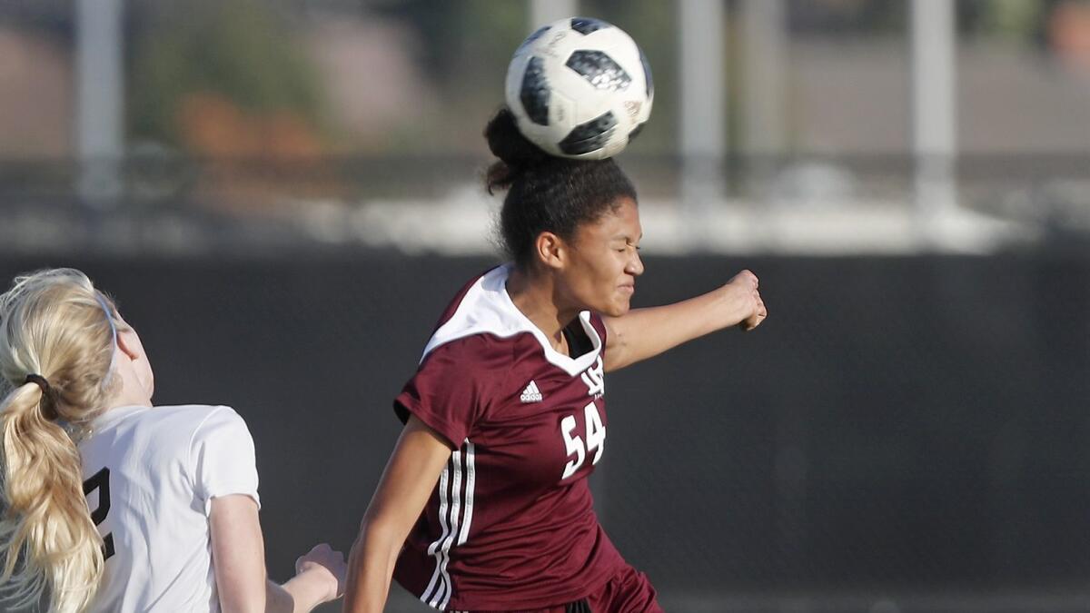 Laguna Beach's Reilyn Turner (54) heads the ball against Corona del Mar's Julianne Bartz during the first half of a nonleague match on Jan. 5, 2018.