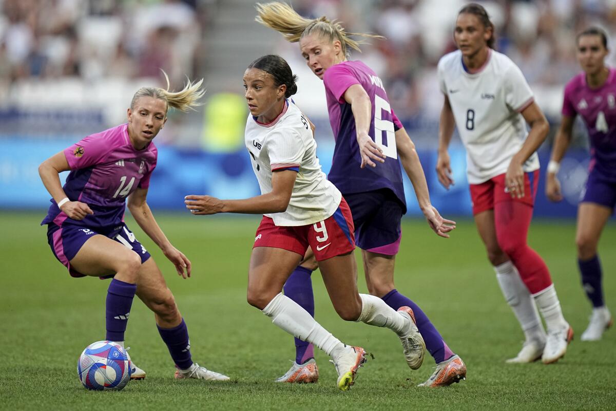 American Mallory Swanson drives the ball next to Germany's Elisa Senss and Janina Minge during a 2024 Summer Olympics 