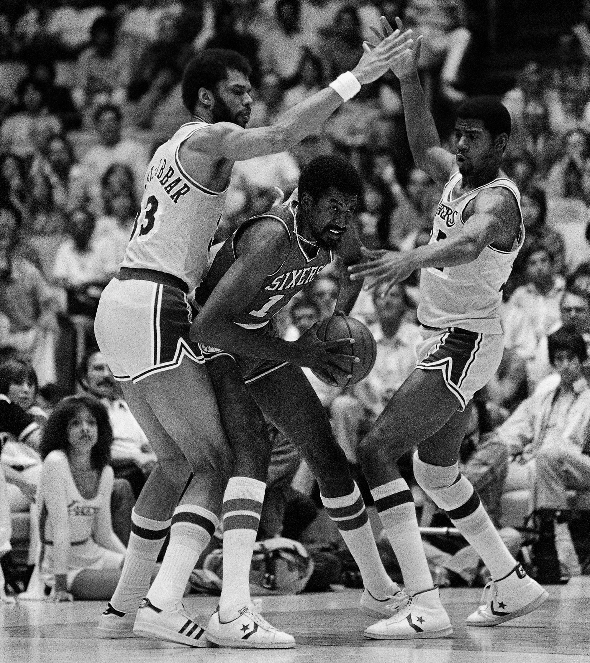 Lakers stars Kareem Abdul-Jabbar, left, and Magic Johnson defend against Philadelphia 76ers forward Caldwell Jones.